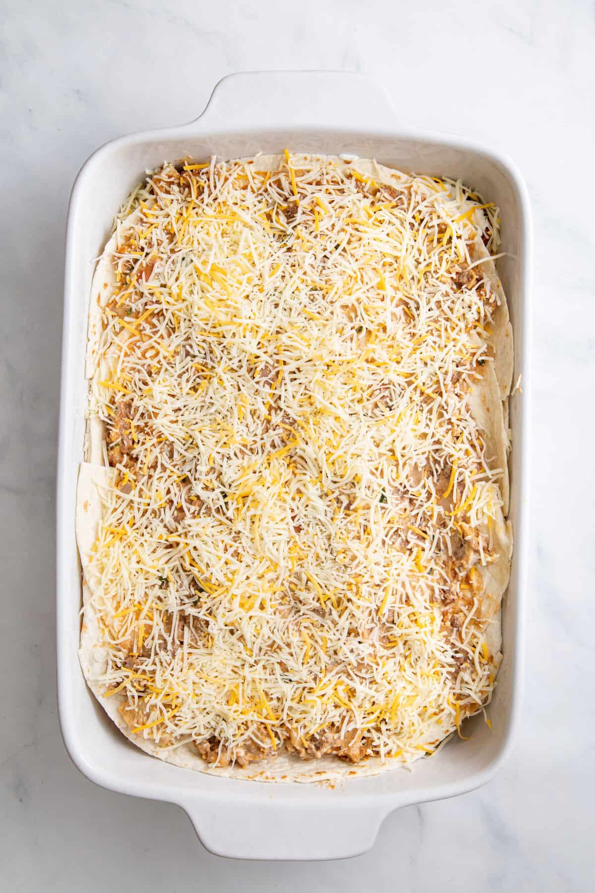 step 4 to make burrito casserole, repeat layer finishing with shredded cheese on top