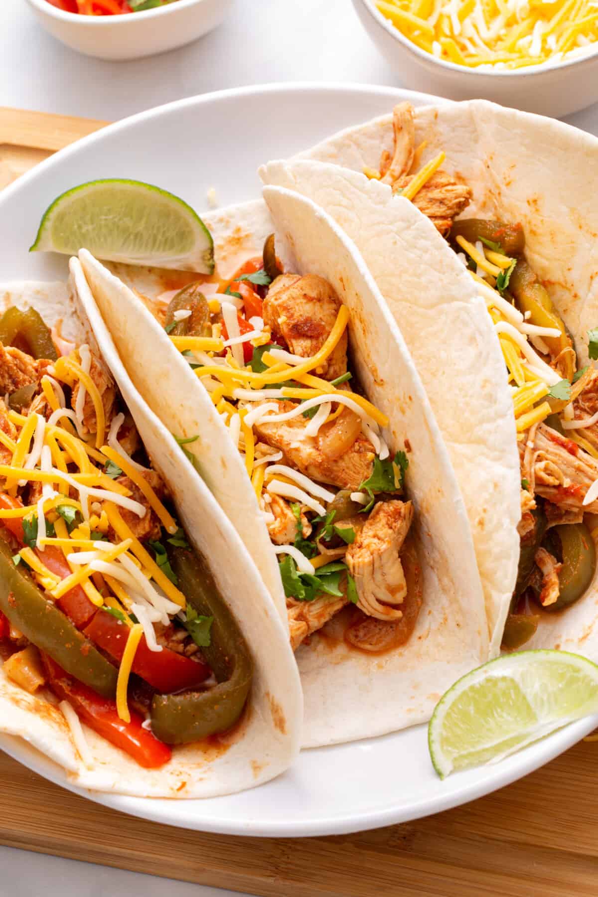 Three tortilla shells stuffed with crockpot chicken fajitas.