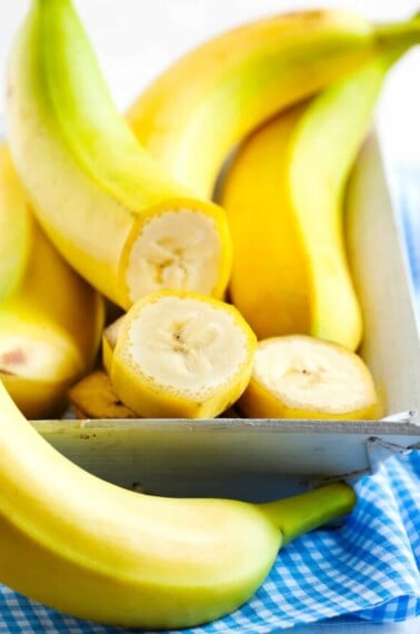 Bananas in a dish, with one cut into slices.