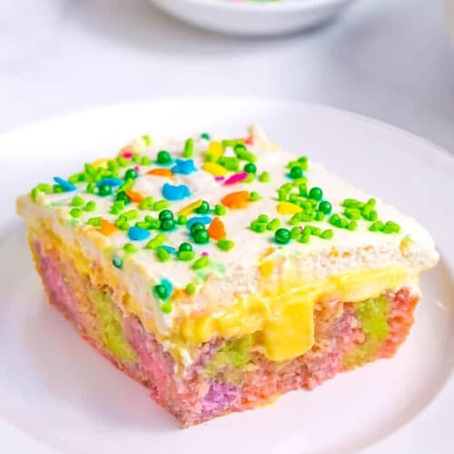 A slice of Easter poke cake topped with sprinkles on a plate.