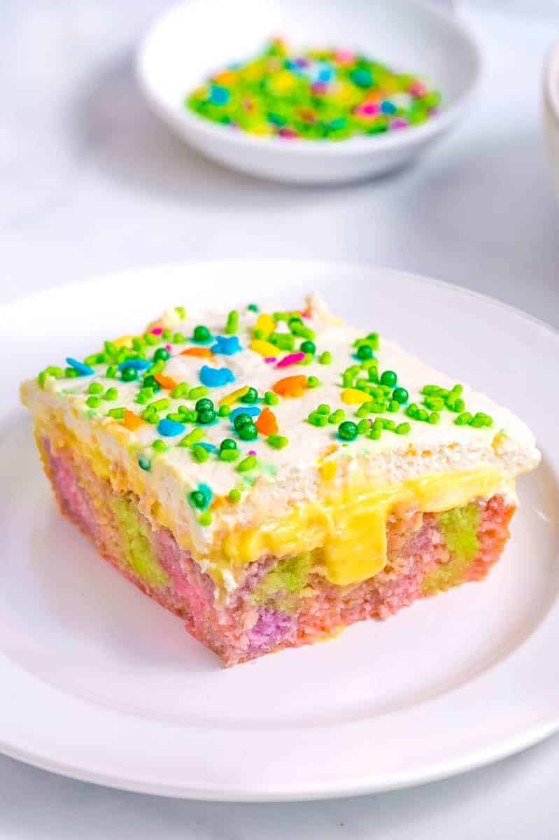 A slice of Easter poke cake topped with sprinkles on a plate.