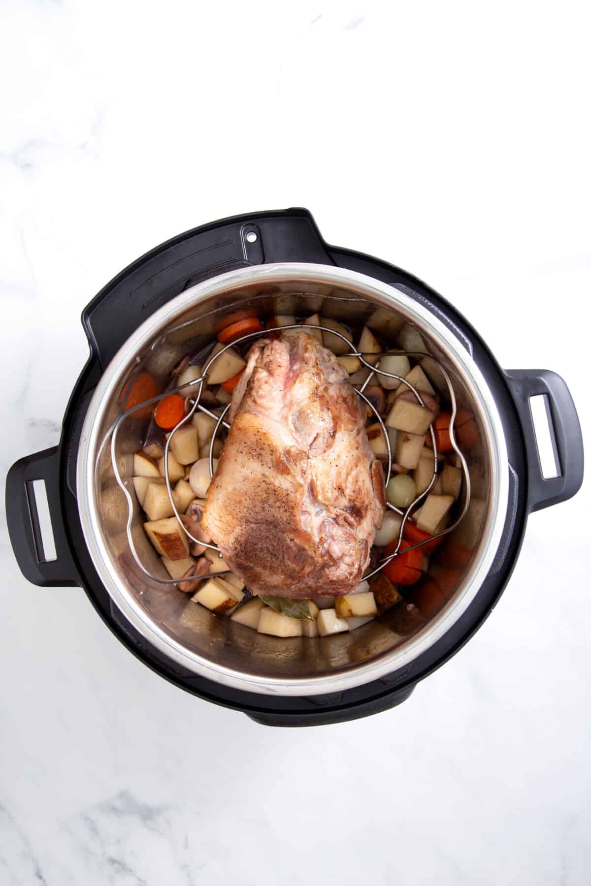 step 3 to make instant pot pork roast, place the pork roast on top of the veggies and pressure cook.