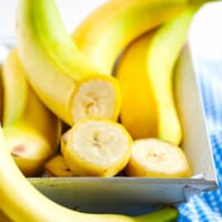 Bananas in a dish, with one cut into slices.