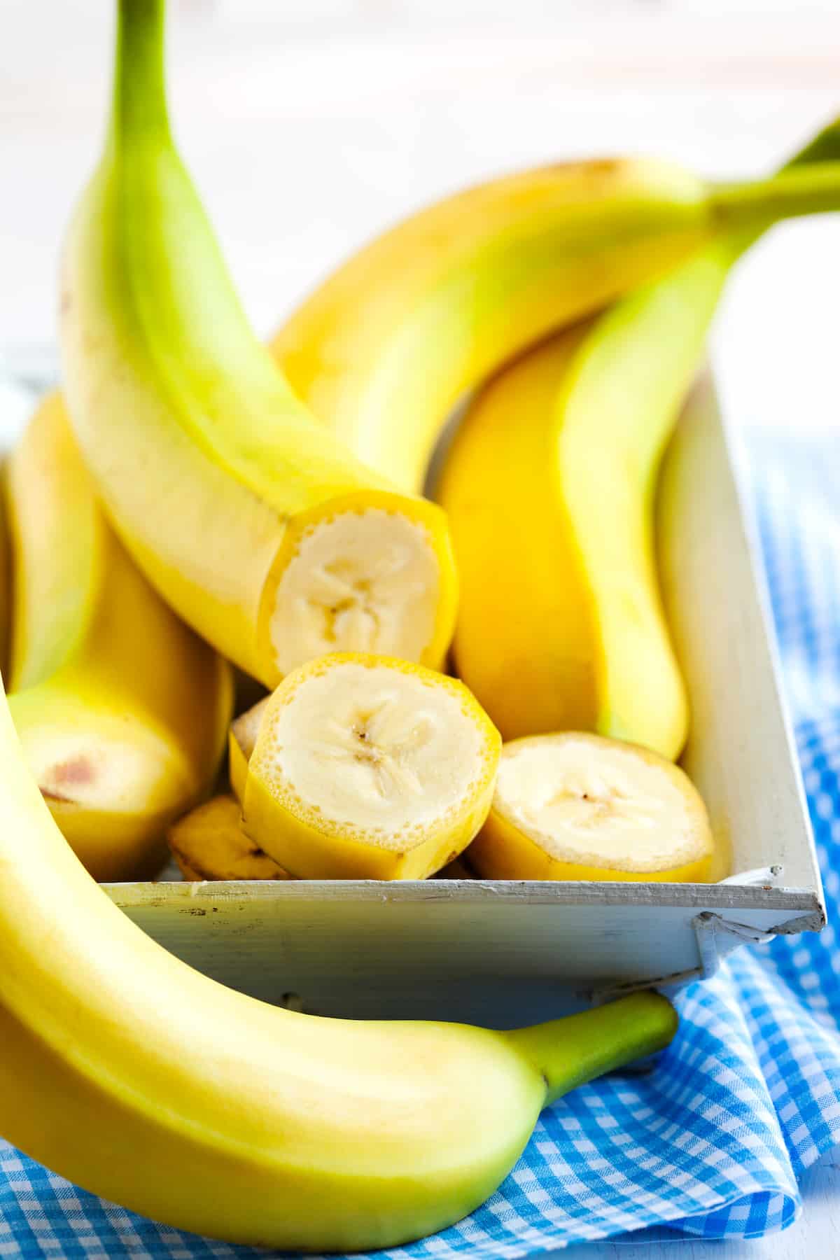 Bananas in a dish, with one cut into slices