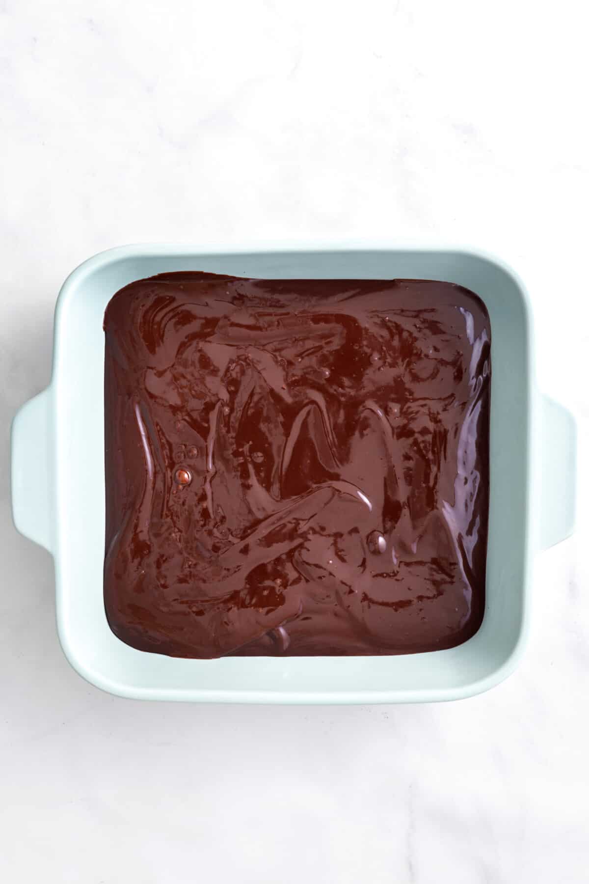 step 2 to make s'mores dip, layer melted chocolate mixture to the bottom of a 9 by 9 baking dish.
