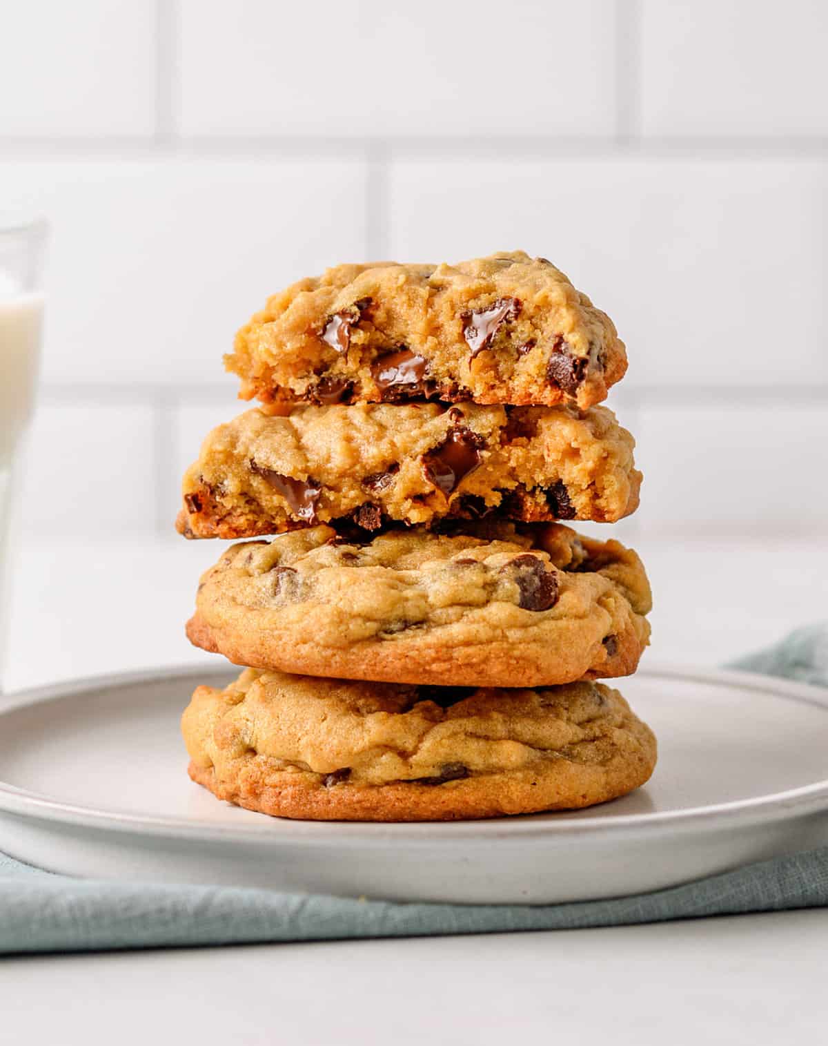 stack of four chocolate chip pudding cookies sitting on a grey round plate