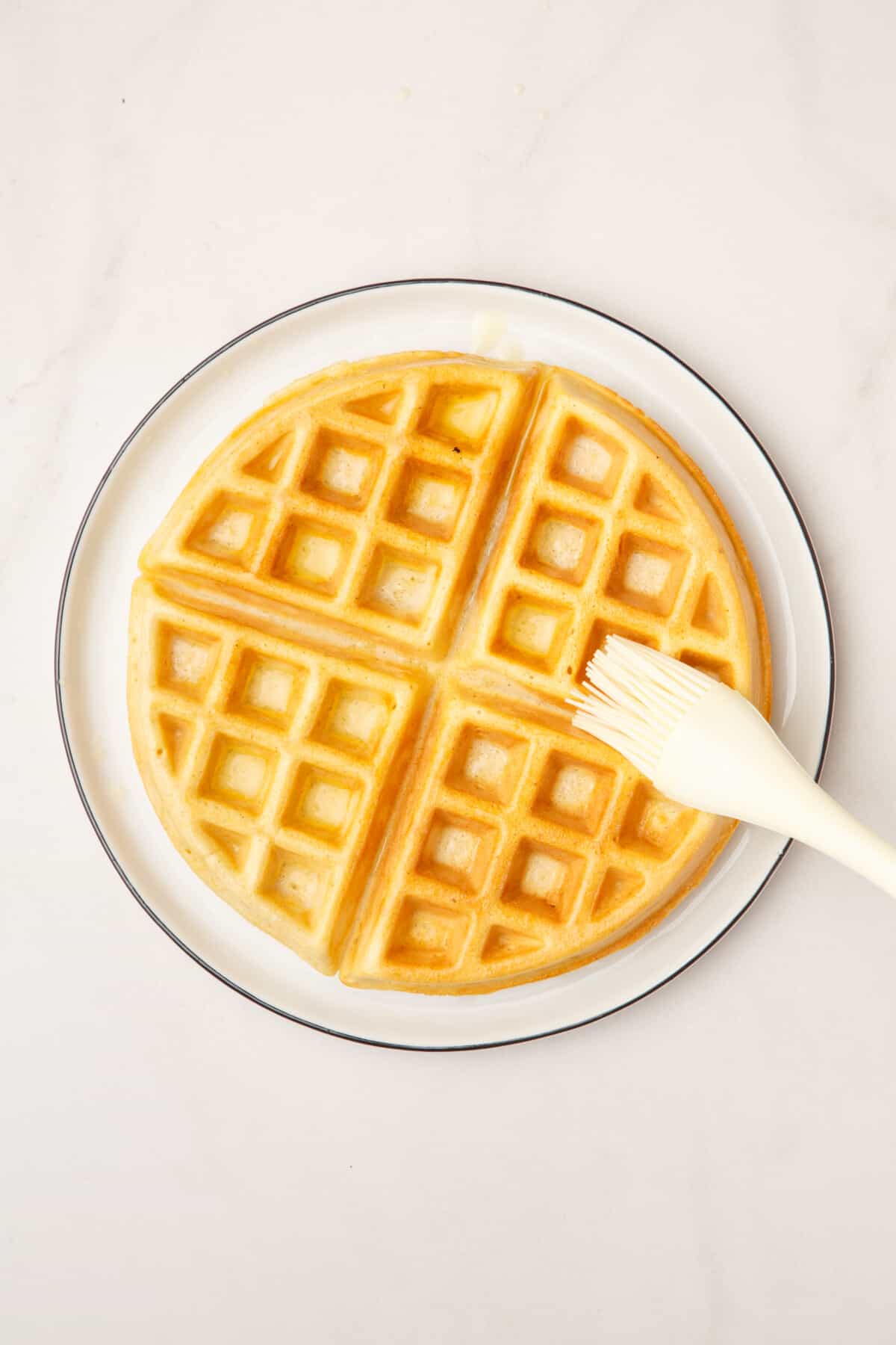 kitchen brush dousing a waffle with butter.