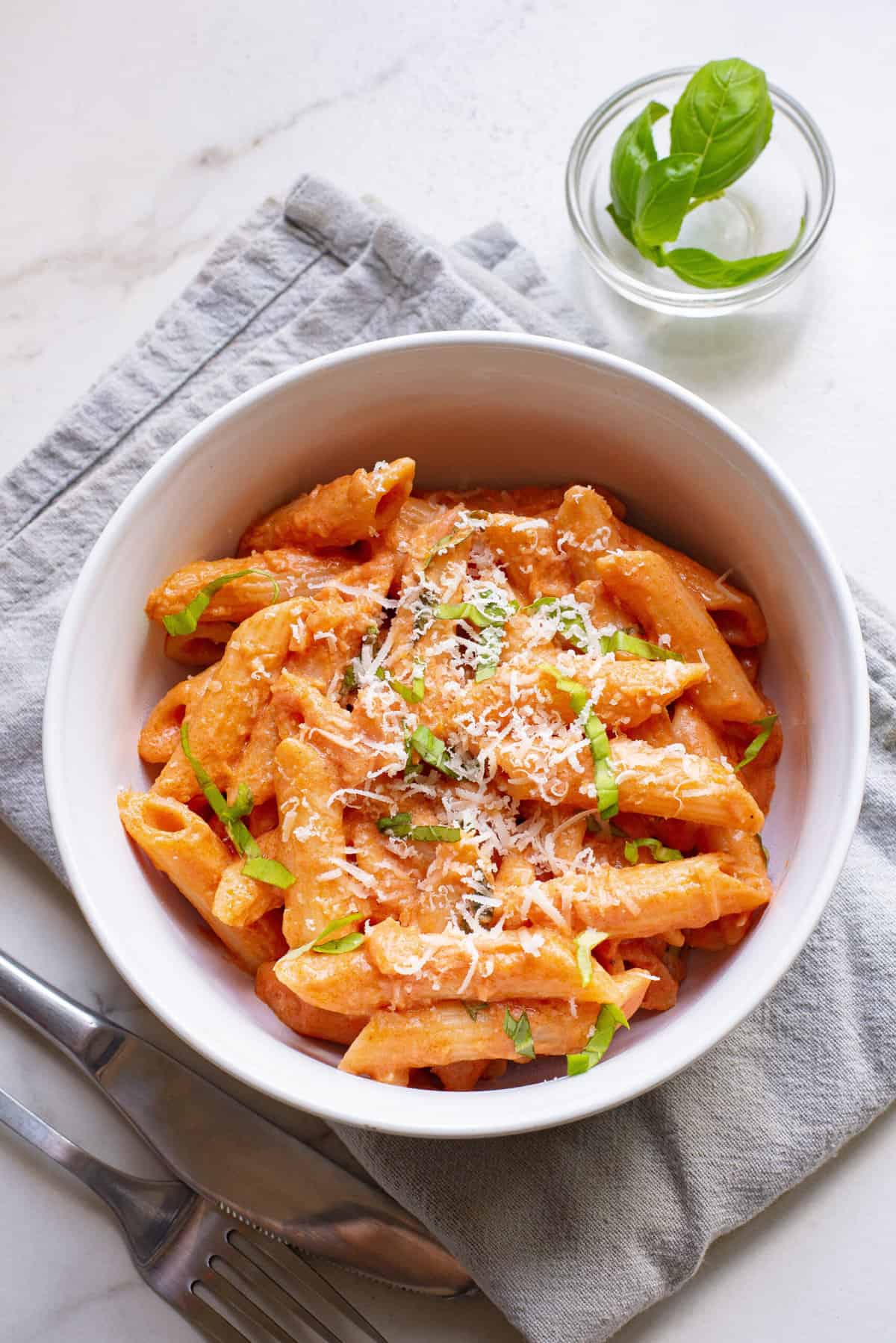 top down image of creamy tomato pasta served in a white round bowl