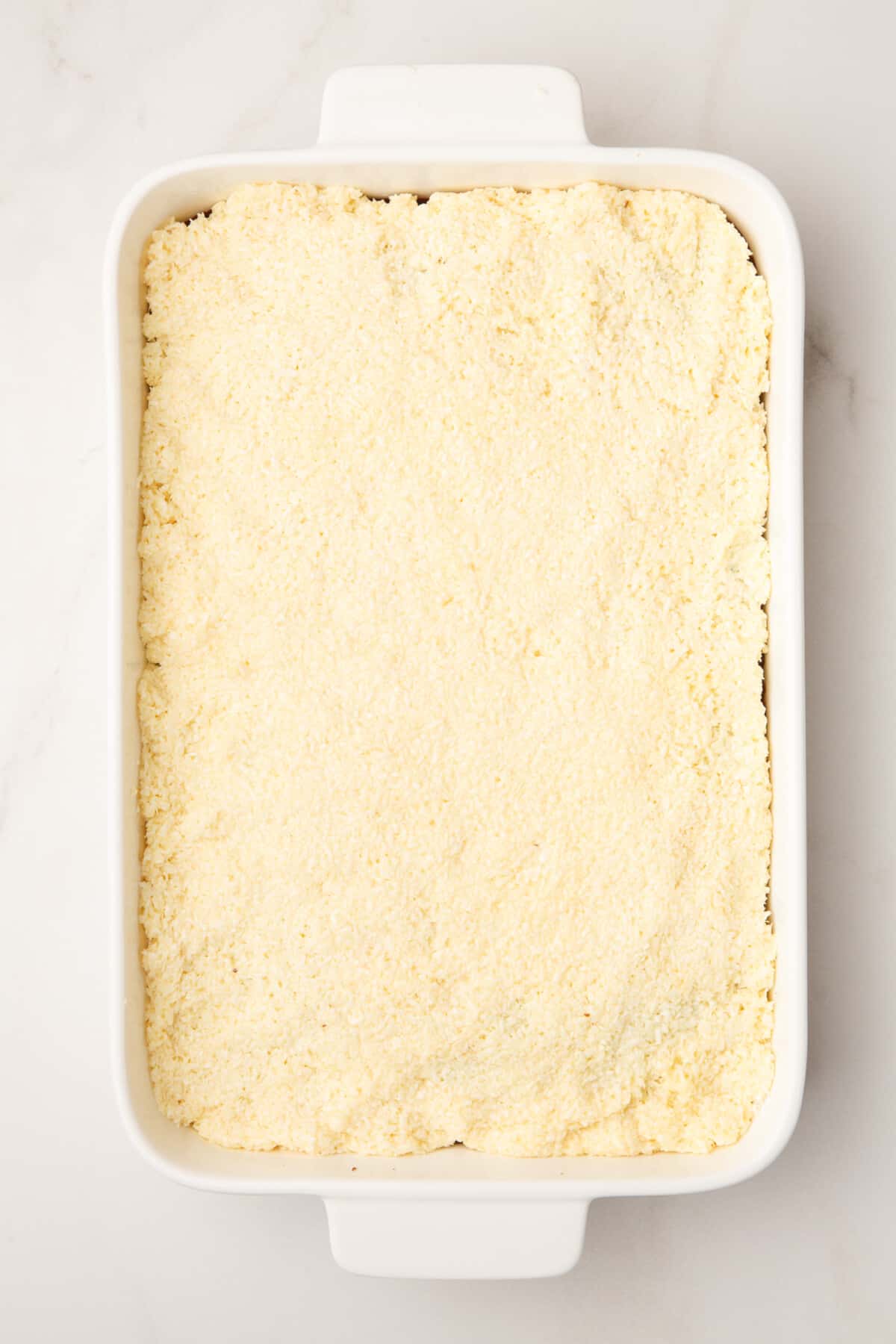 coconut topping layered on a chocolate cake in a 9x13 casserole dish.
