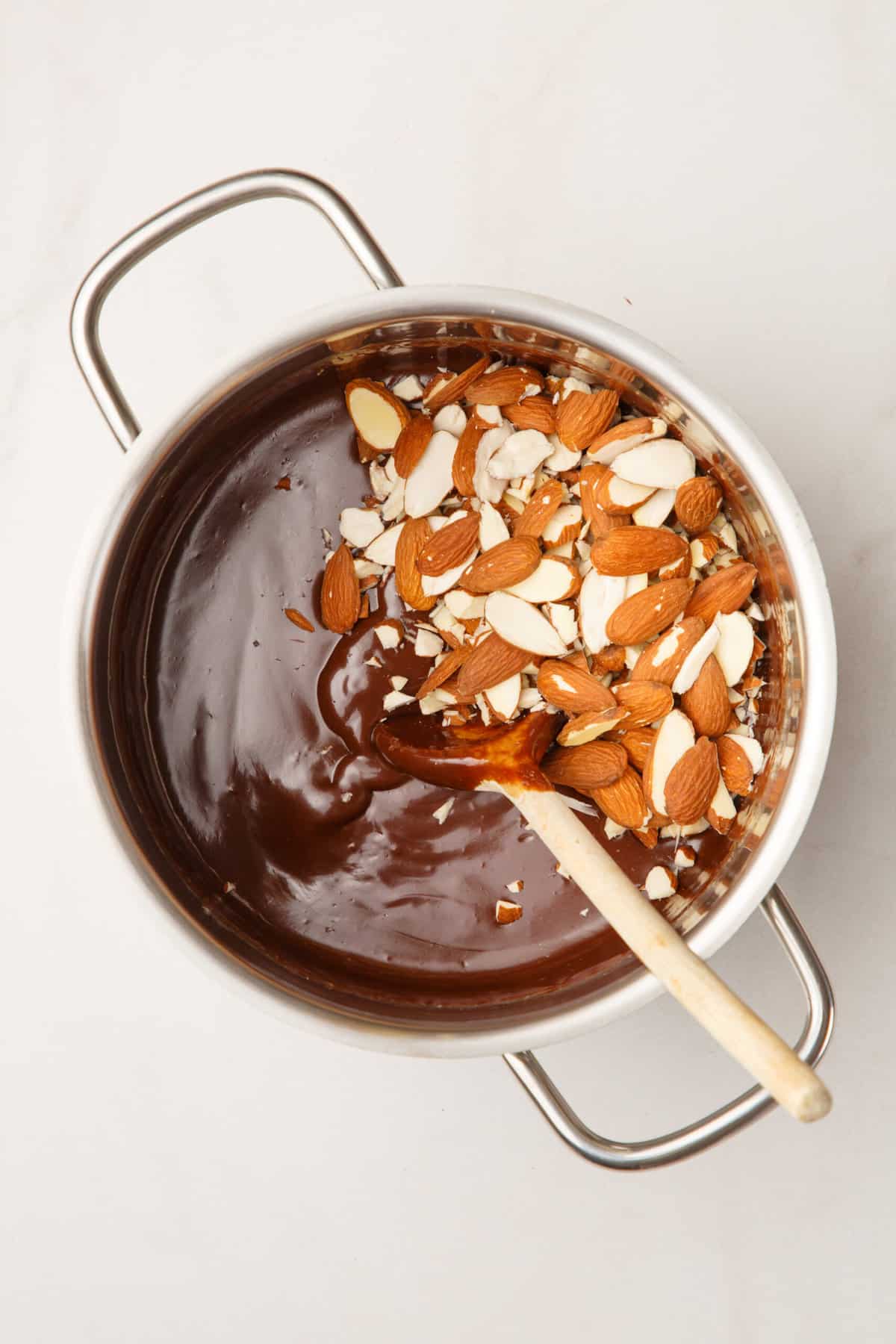 melted chocolate and sliced almonds in a stainless steel saucepan