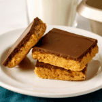 Three no-bake peanut butter bars on a plate.