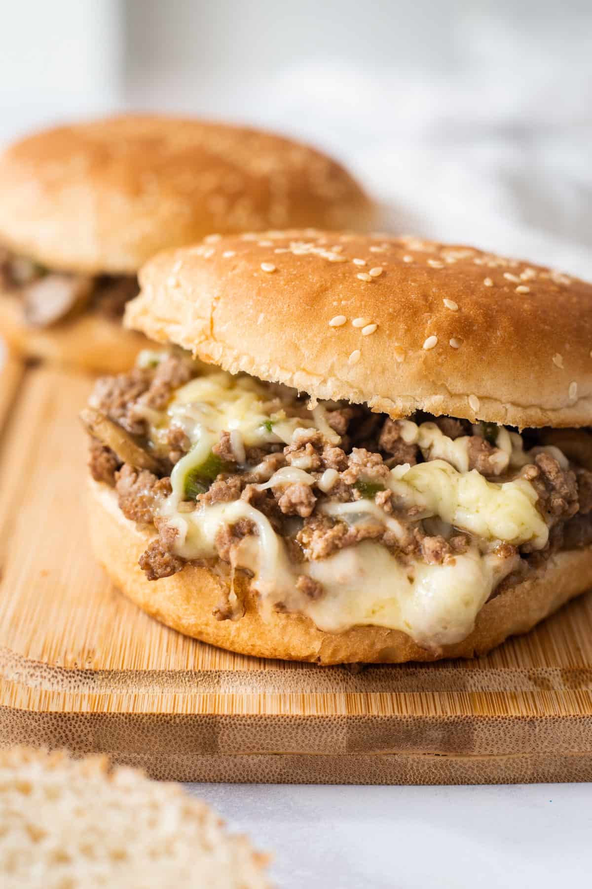 close up image of a philly cheesesteak sloppy joe sandwich sitting on a wood cutting board