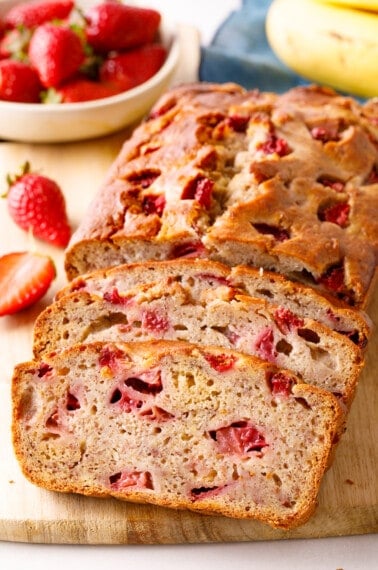 A loaf of strawberry banana bread with two slices cut.