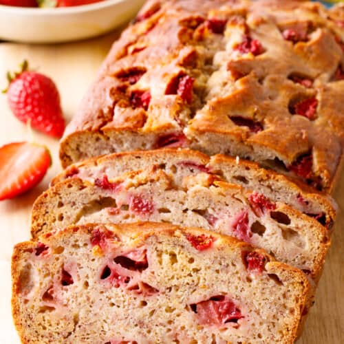 A loaf of strawberry banana bread with two slices cut.