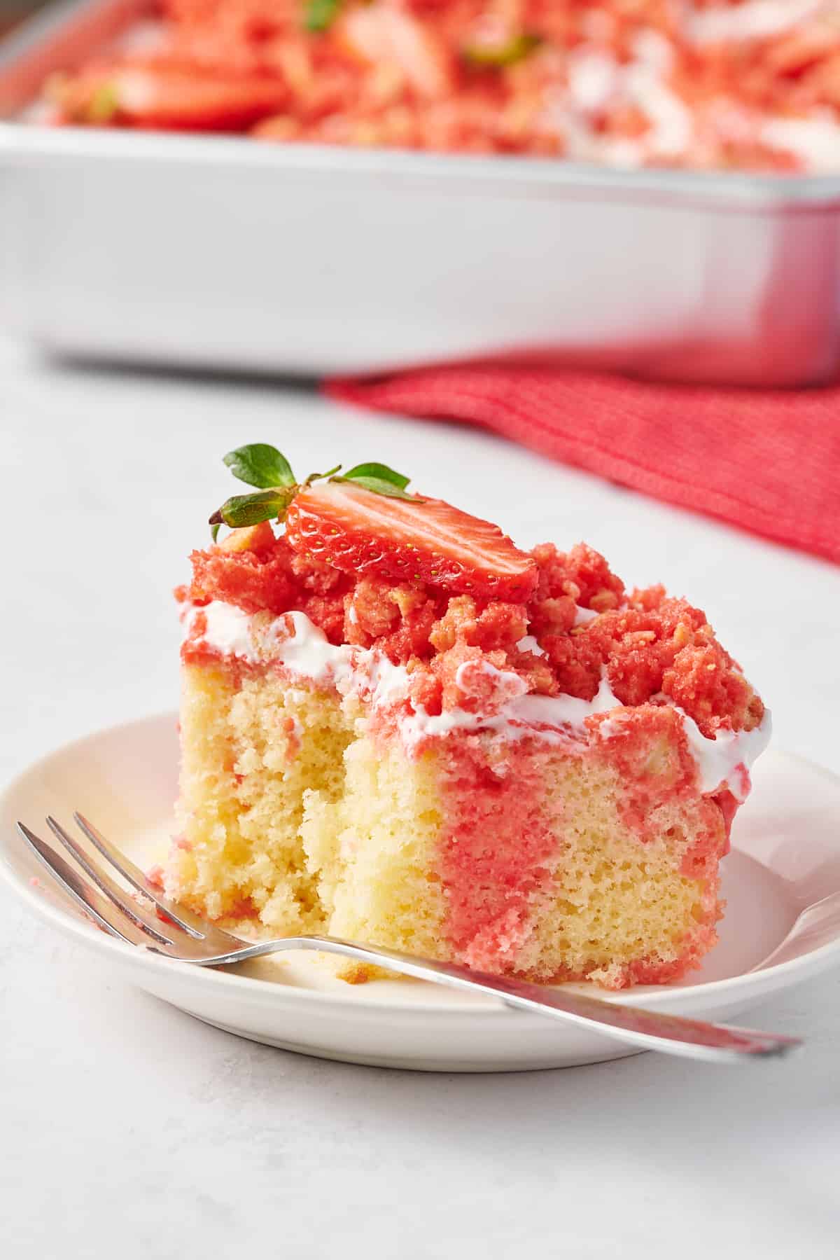 close up image of a serving of strawberry crunch poke cake