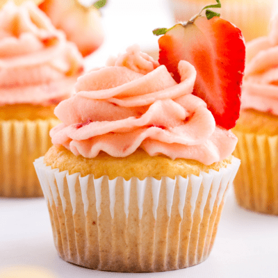 Strawberry lemon cupcakes with strawberry frosting and a halved strawberry.