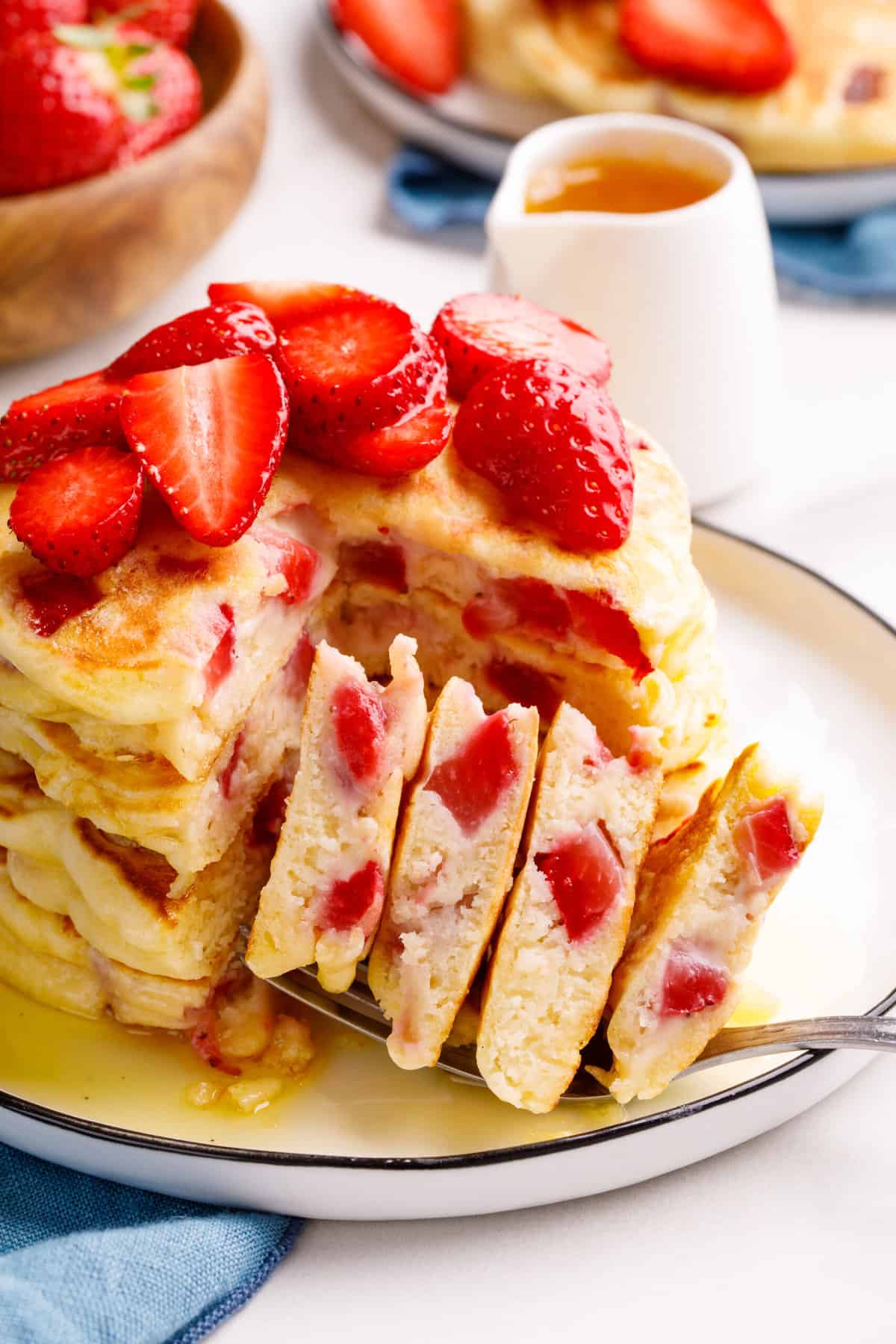 close up image of a stack of four strawberry pancakes cut into to show the cross section