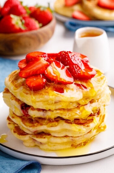 A stack of strawberry pancakes topped with chopped strawberries.