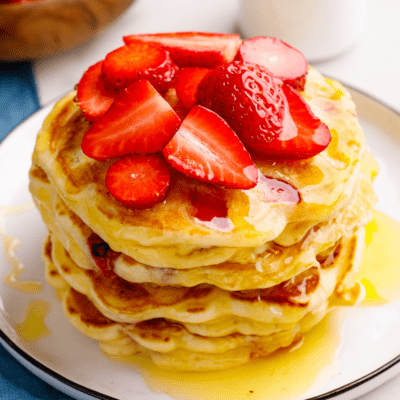 A stack of strawberry pancakes topped with sliced strawberries.