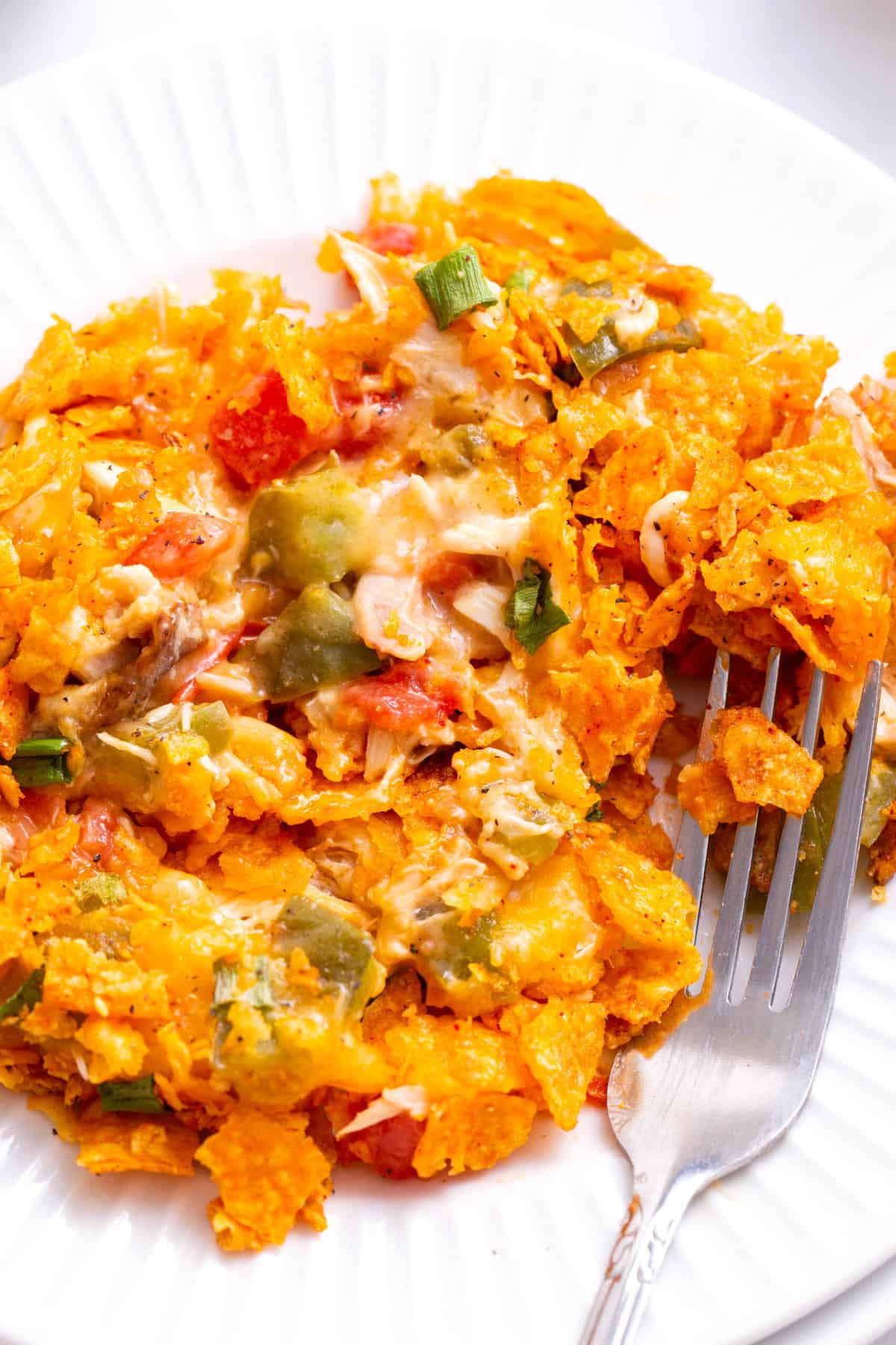 close up image of a plate of dorito chicken casserole with a silver fork