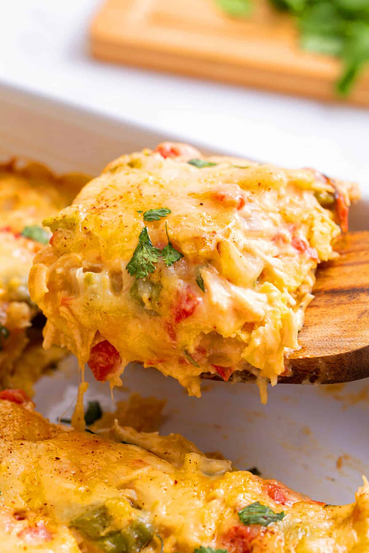 close up image of a slice of king ranch chicken casserole sitting on a wood spatula