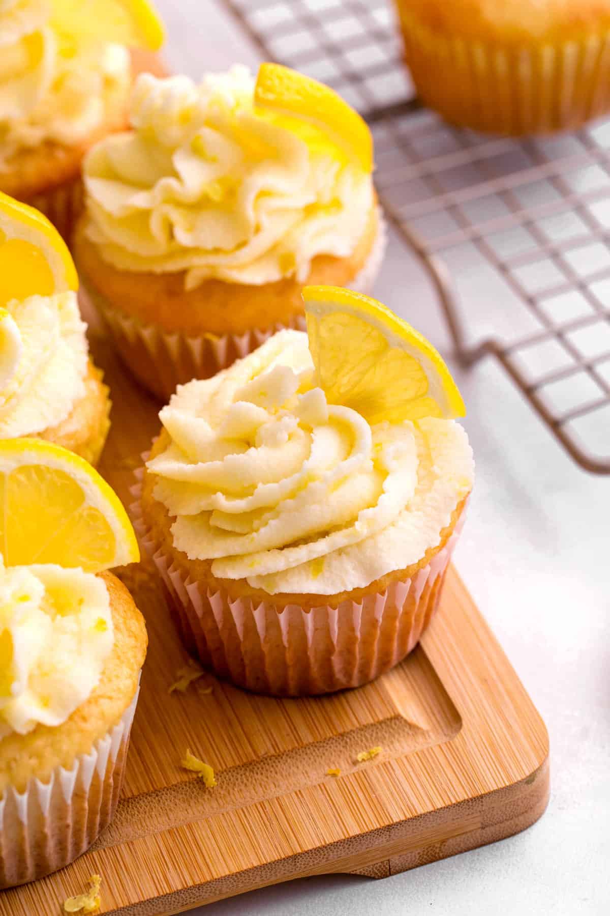 lemon cupcakes sitting on a wood cutting board