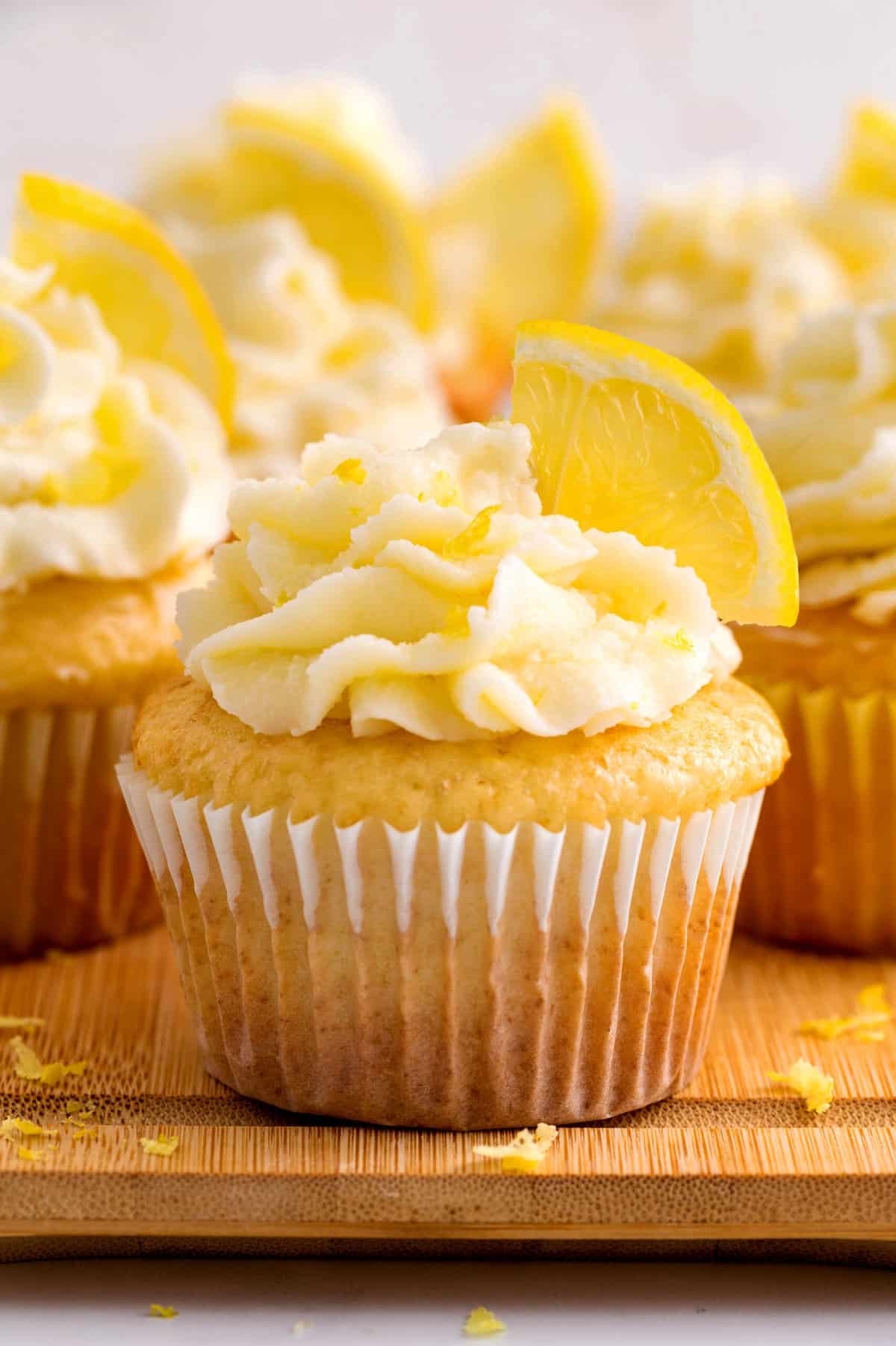 close up image of a lemon cupcake with frosting and a fresh slice of lemon