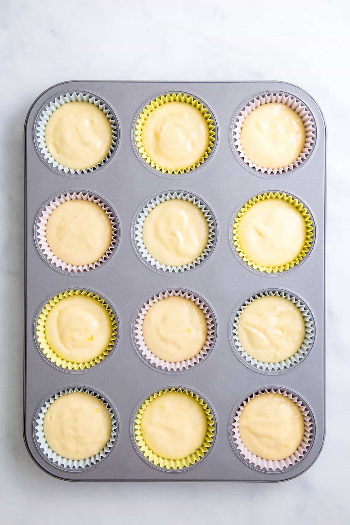lemon cupcake batter filled in twelve cupcake liners in a muffin tin