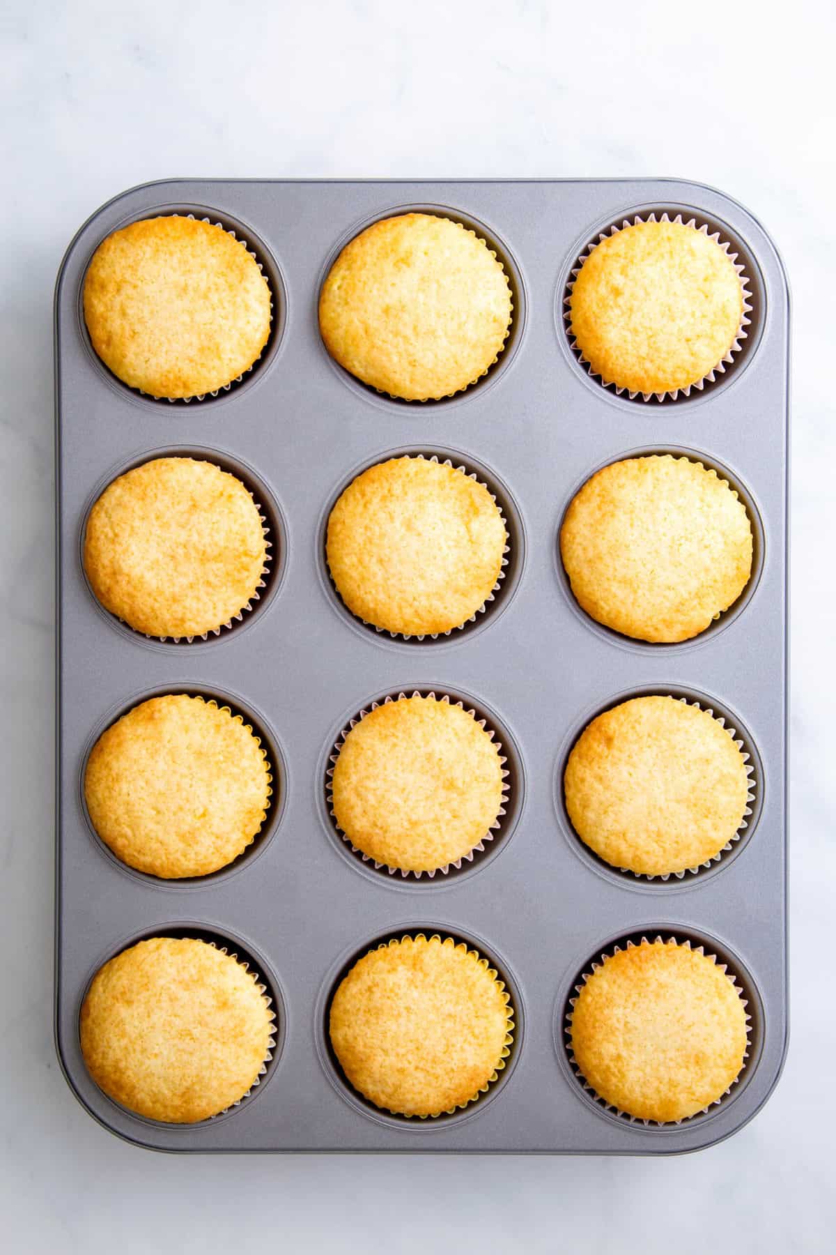 12 baked lemon cupcakes in a muffin tin