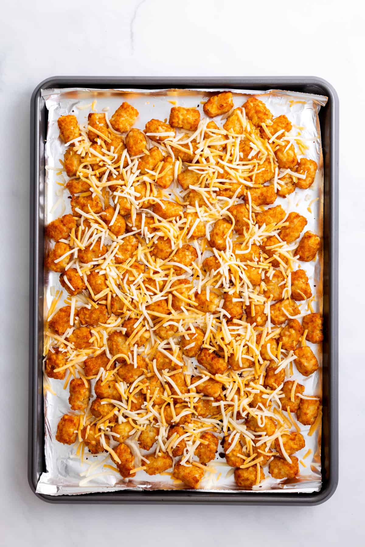 step 2 to make loaded tater tots, sprinkle shredded cheese over the tater tots