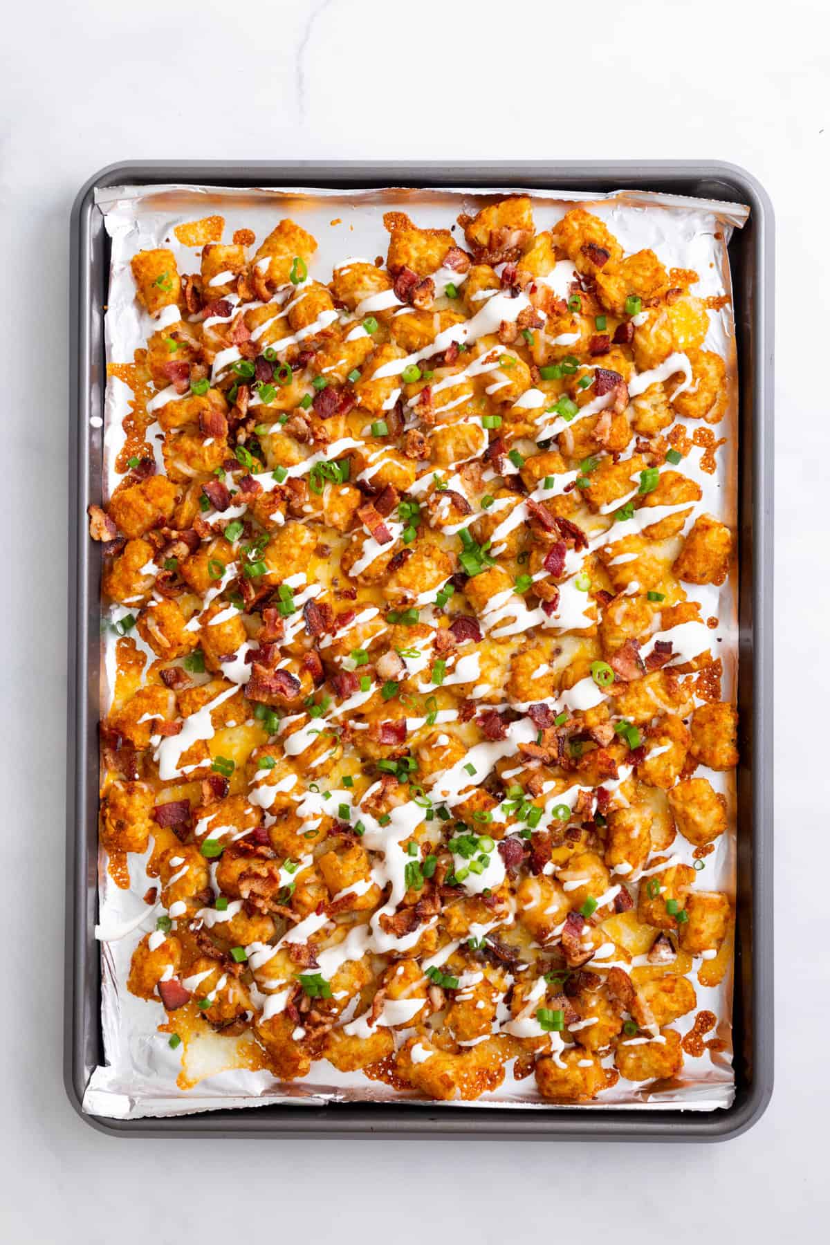 step 4 to make loaded tater tots, top with chopped bacon pieces, green onion and sour cream