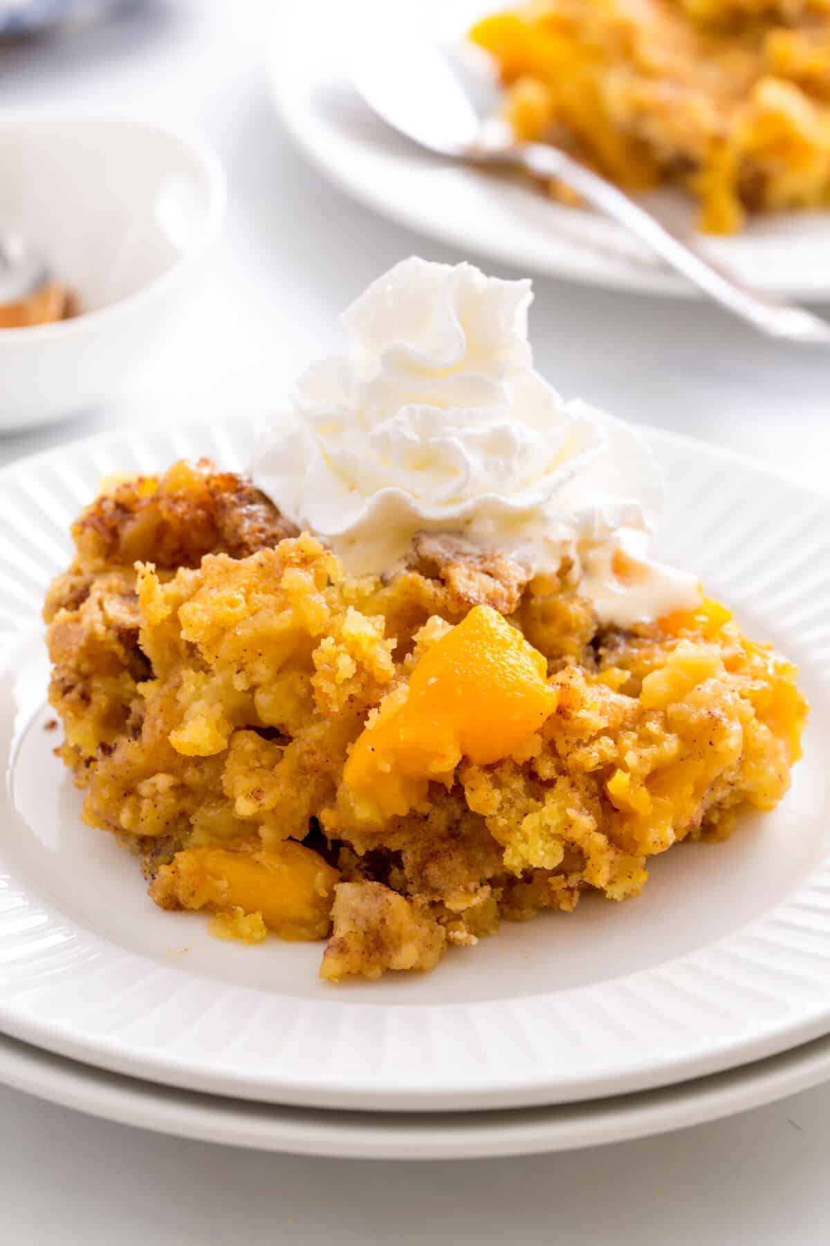peach cobbler with cake mix on a white plate with cool whip. 