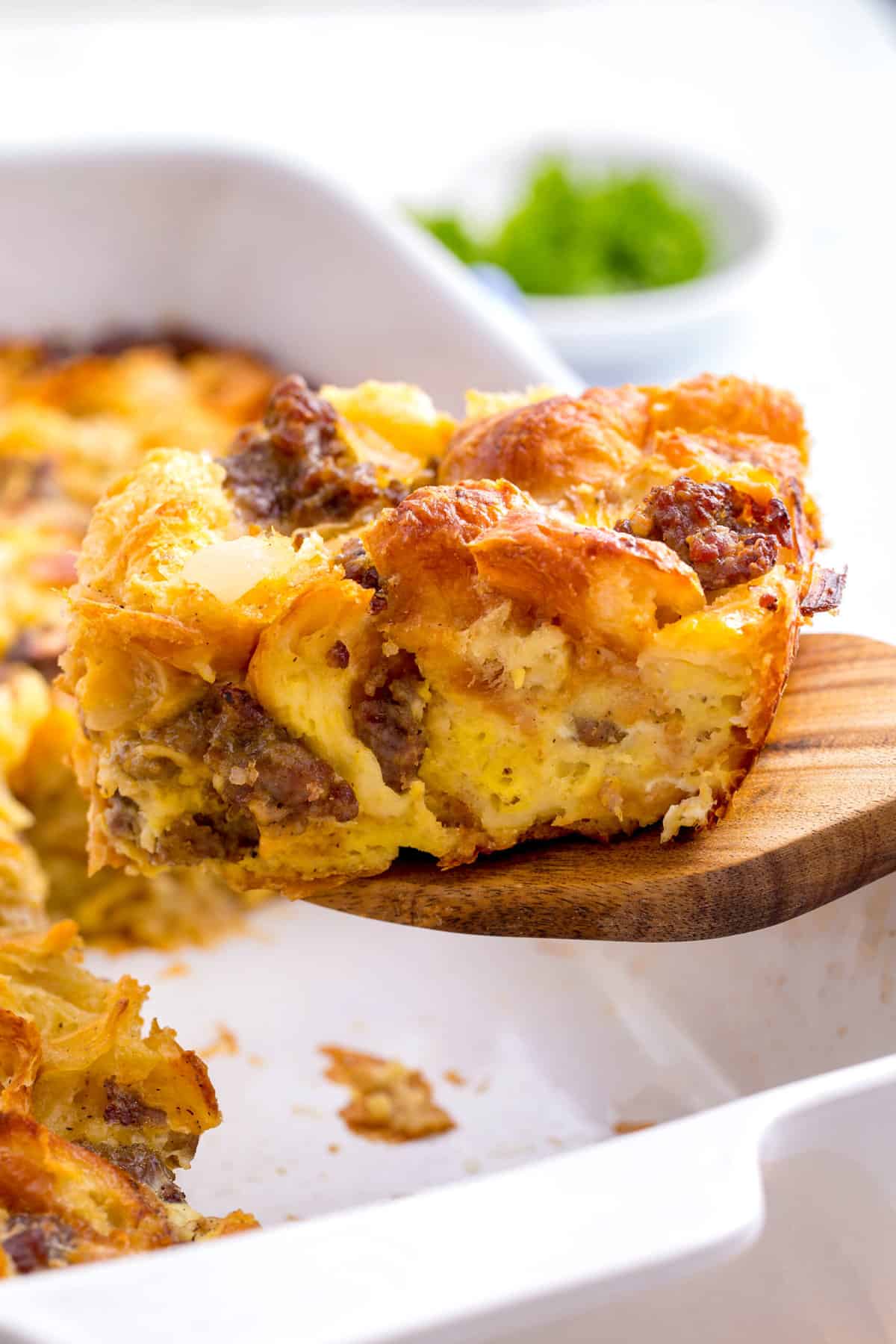 serving of sausage croissant breakfast casserole sitting on a wooden spatula