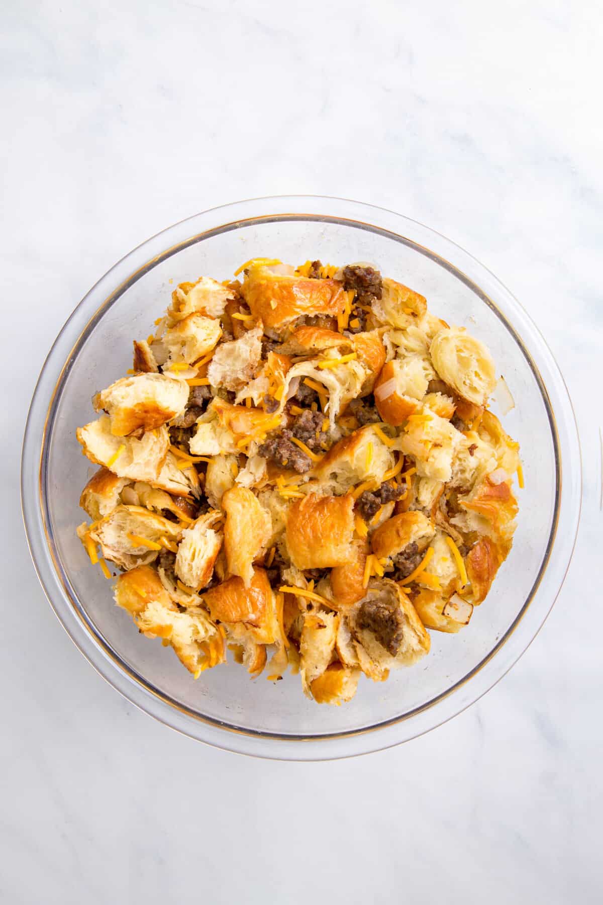 glass bowl fill of stale pieces of bread and cooked ground pork, onions and shredded cheese