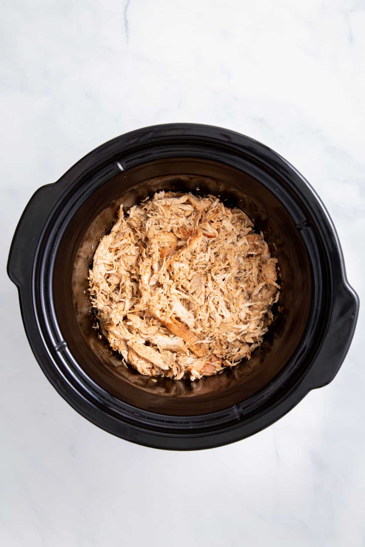 cooked shredded chicken in a slow cooker.
