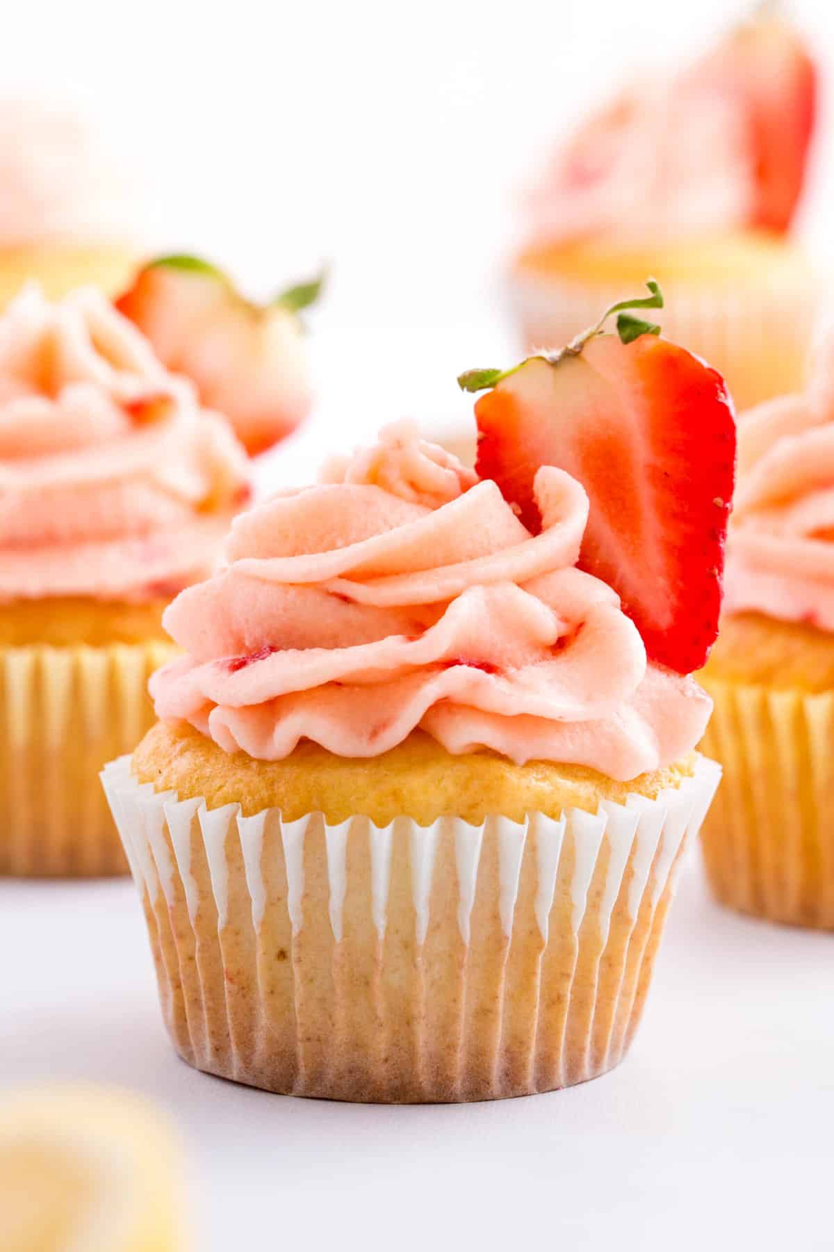 side shot of a strawberry lemon cupcake topped with a fresh strawberry half