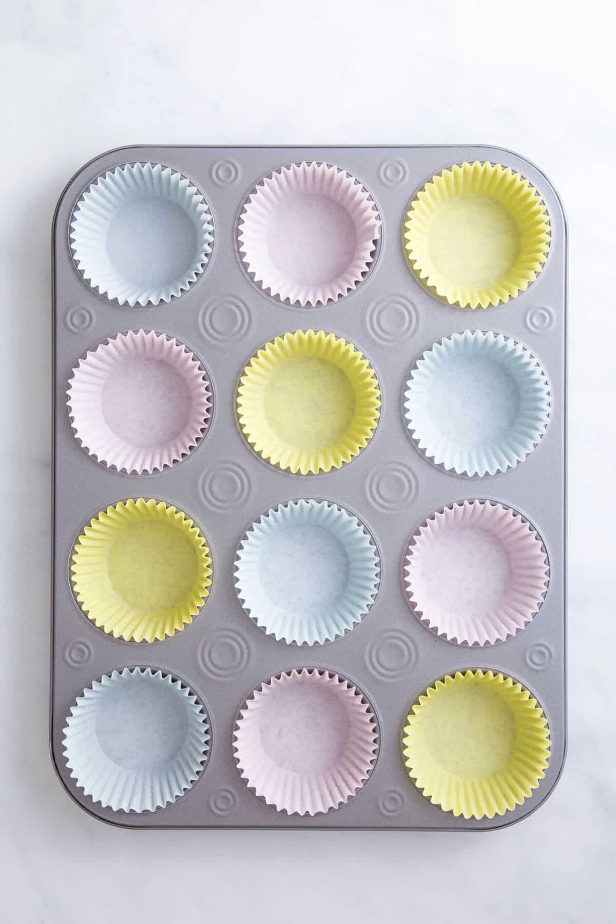 cupcake tin lined with 12 pastel colored cupcake liners. 