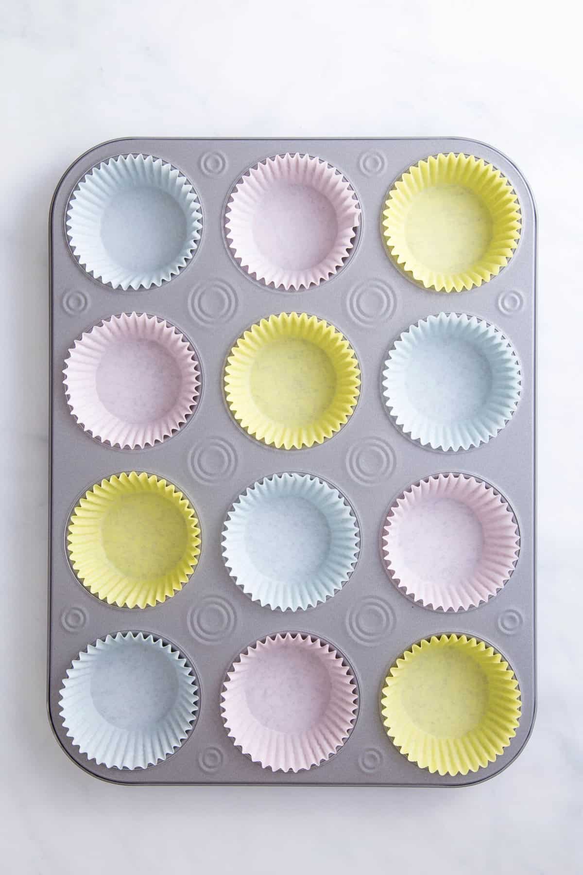 cupcake tin lined with 12 pastel colored cupcake liners