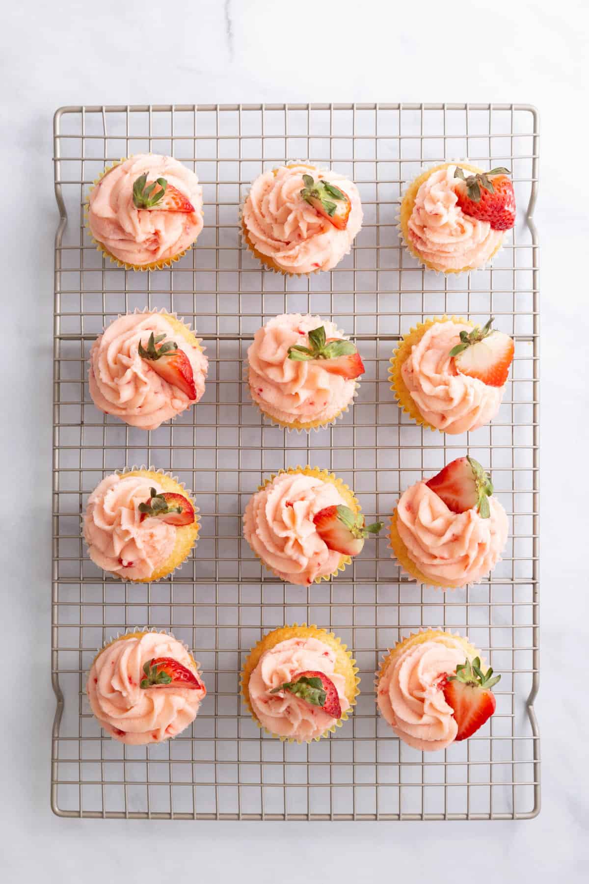 12 lemon strawberry cupcakes cooling on a wire rack