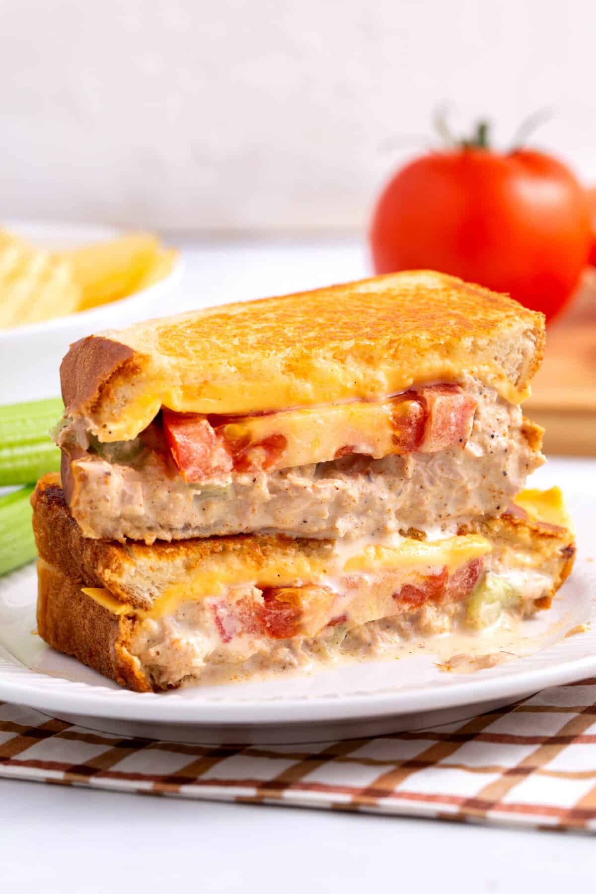 tuna melt sandwich cut in half and stacked on a white round plate