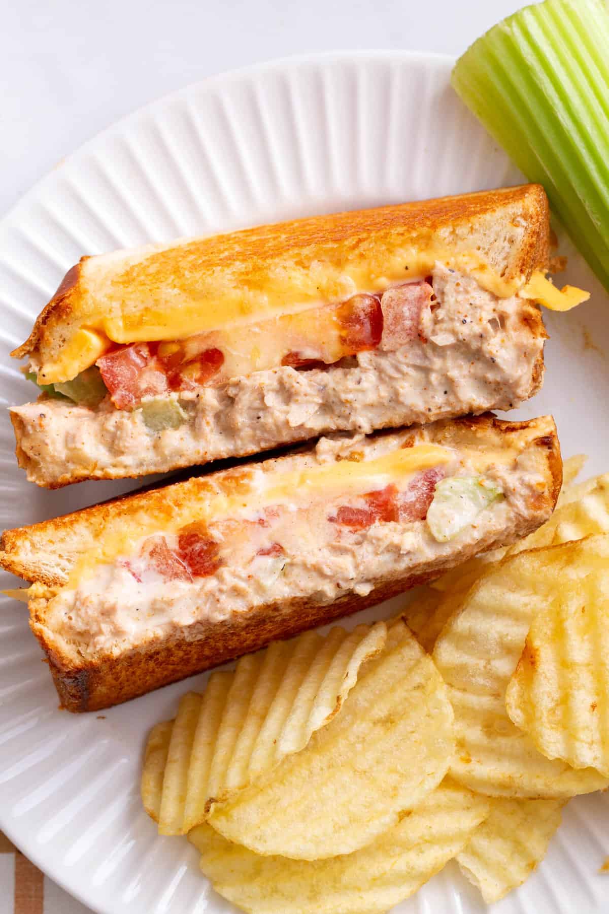 top down image of a tuna melt sandwich cut in half facing up to show the cross section with a side of wavy kettle potato chips