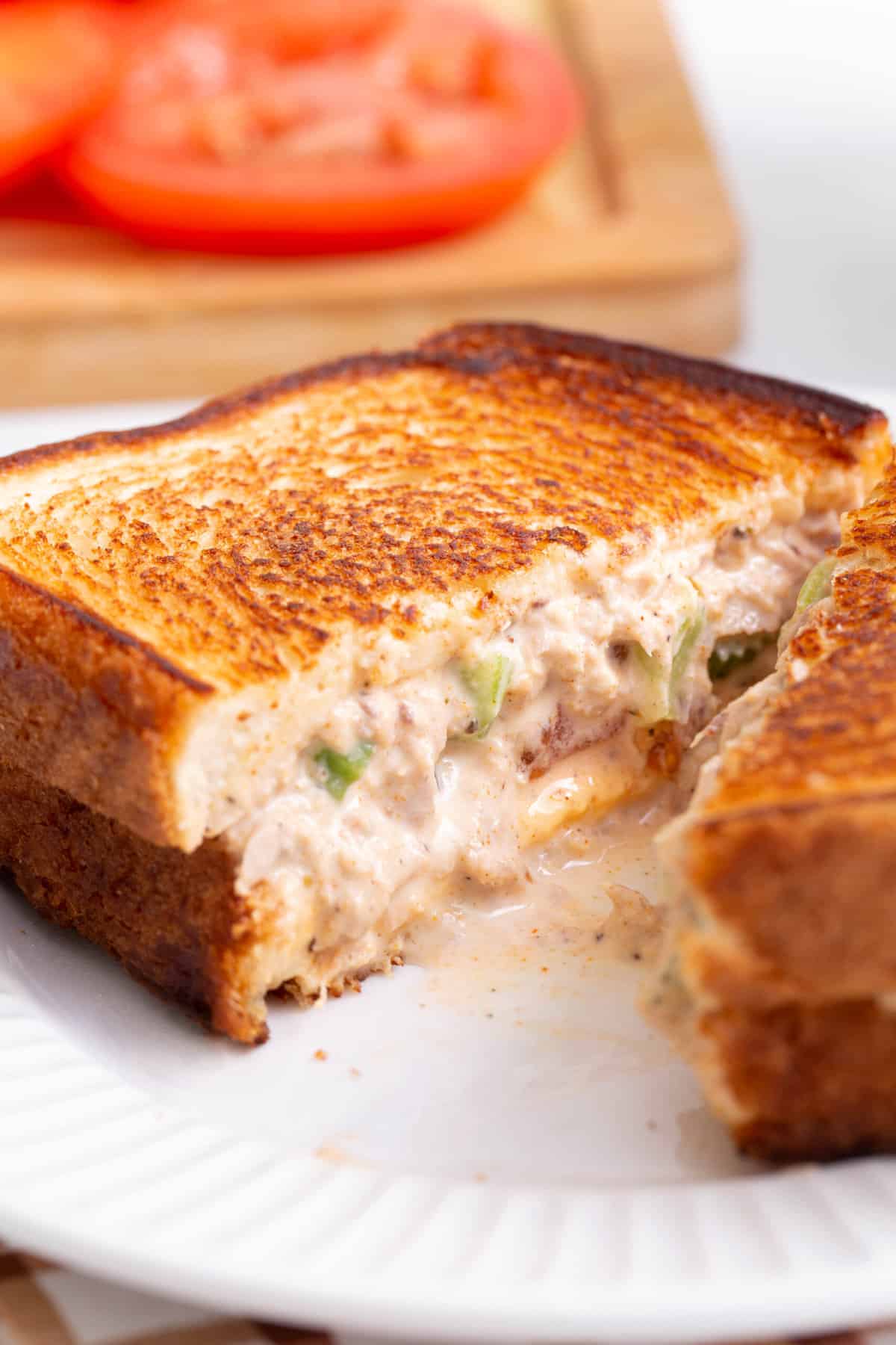 close up image of the cross section of a tuna melt sandwich sitting on a white round plate