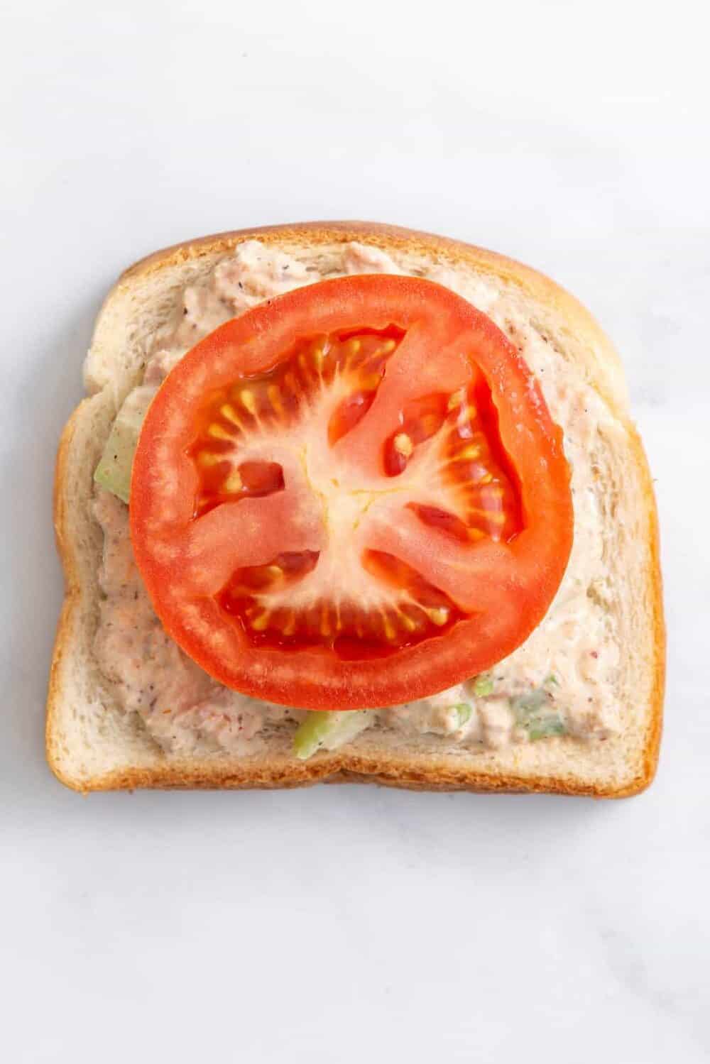 step 2 to make a tuna melt sandwich, place sliced tomatoes on top of the tuna salad on bread