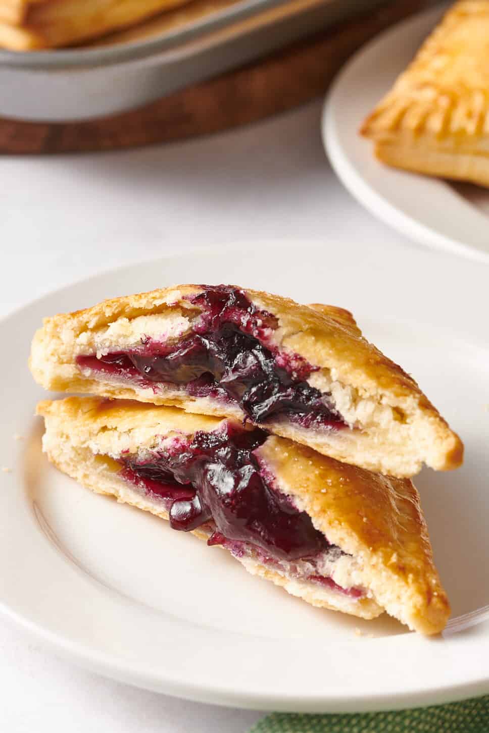 A blueberry hand pie split in half and stacked on a plate. 