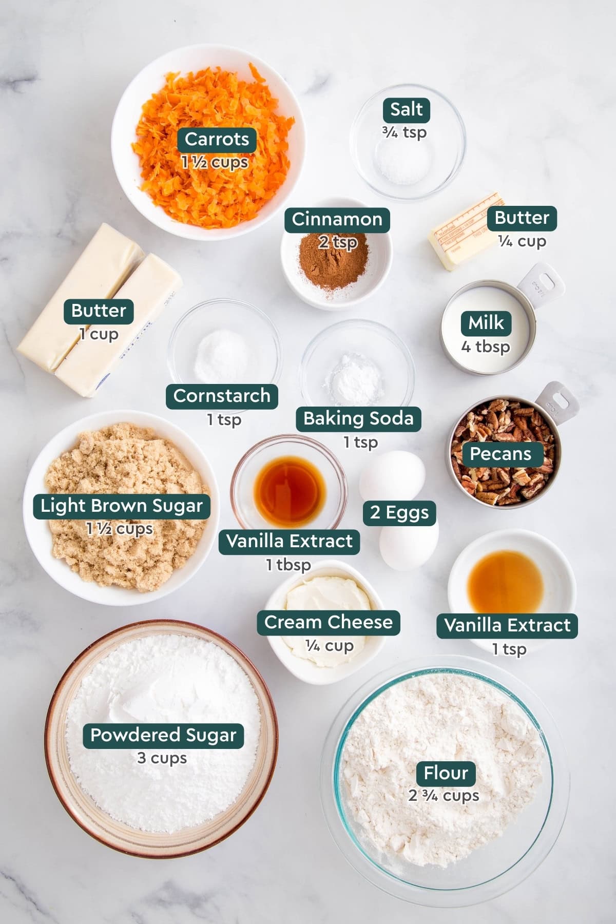 Ingredients for carrot cake cookies, including carrots, salt, cinnamon, butter, milk, cornstarch, baking soda, pecans, eggs, vanilla, brown sugar, cream cheese, flour, powdered sugar.