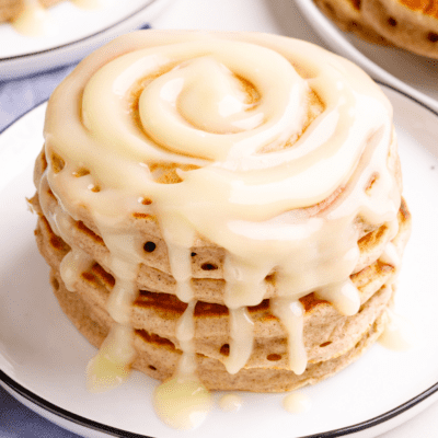 A stack of cinnamon pancakes with cream cheese glaze on a plate.