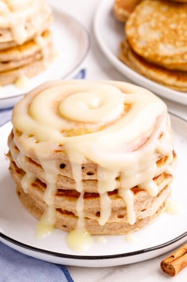 A stack of cinnamon pancakes topped with cream cheese glaze.