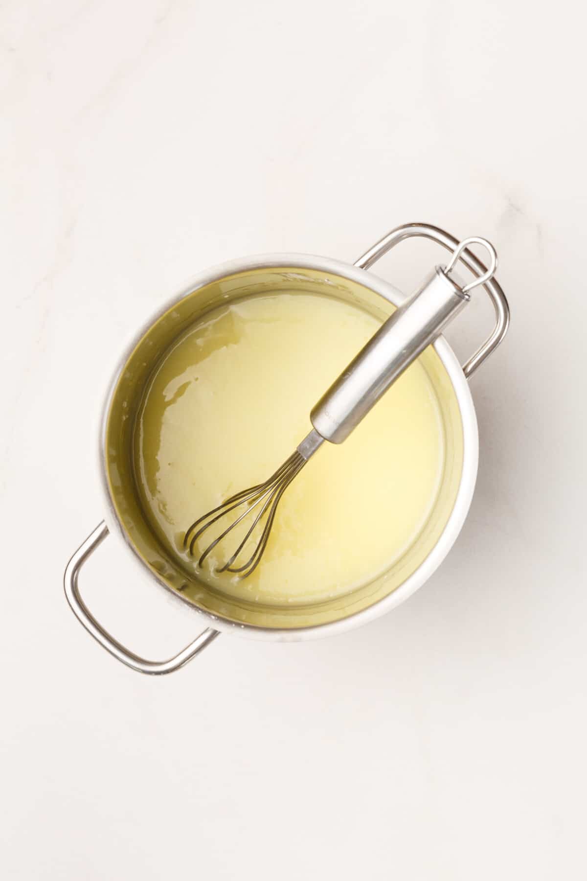 cinnamon pancake glaze ingredients in a stainless steel saucepan with a metal whisk.