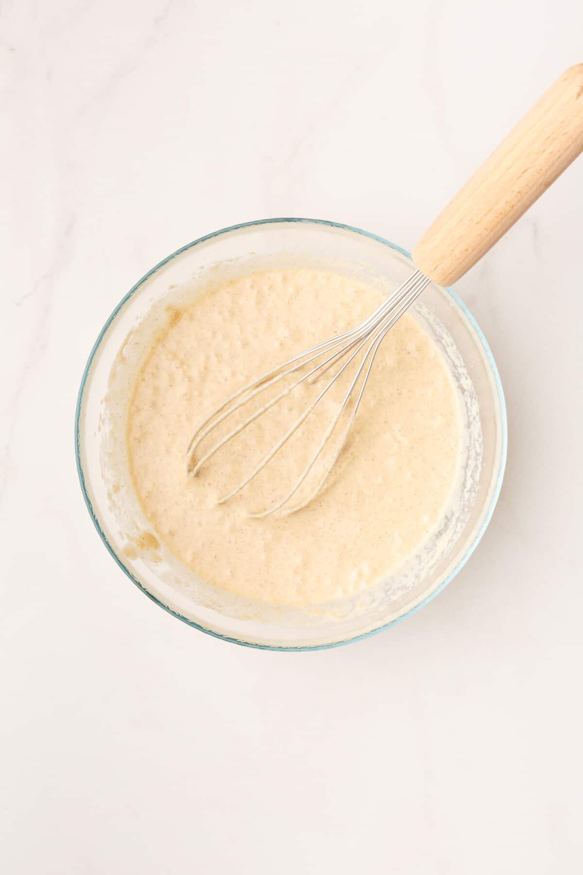 cinnamon pancake batter in a large glass bowl with a whisk.