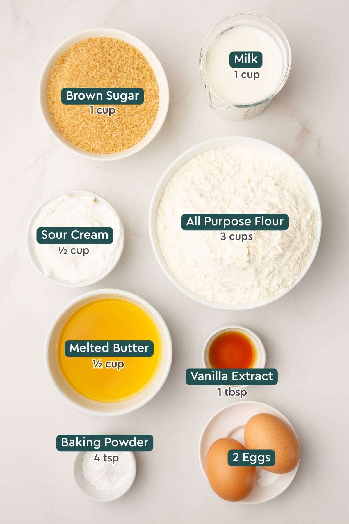Ingredients for cinnamon roll cake, including brown sugar, milk, sour cream, flour, butter, vanilla, baking powder, eggs.
